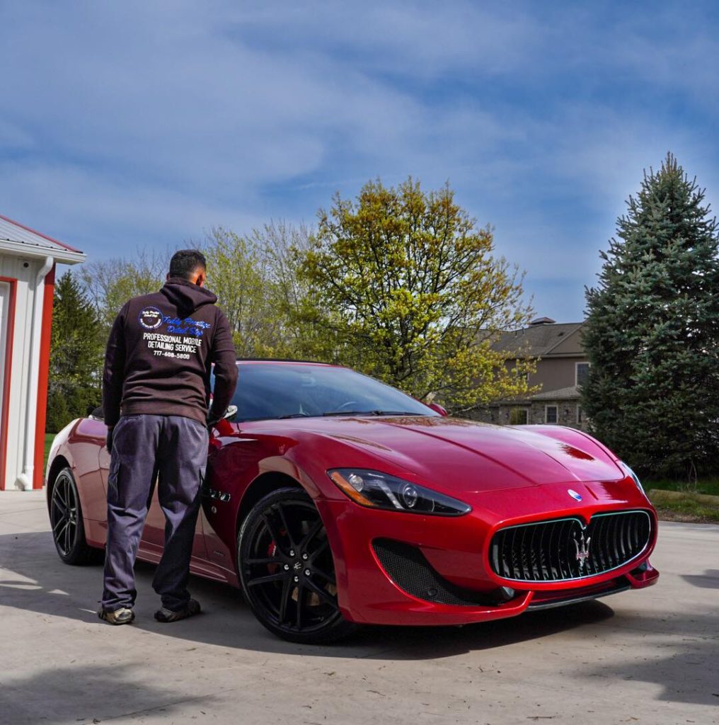 Technician doing mobile paint correction on a red Maserati sports car in a York, PA driveway